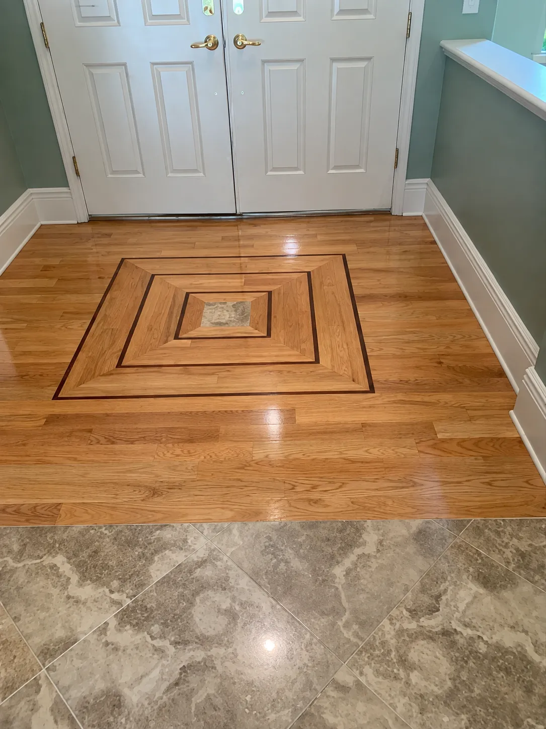 Custom oak medallion inlay with contrasting border and wood-to-tile transition in a Sarasota entry