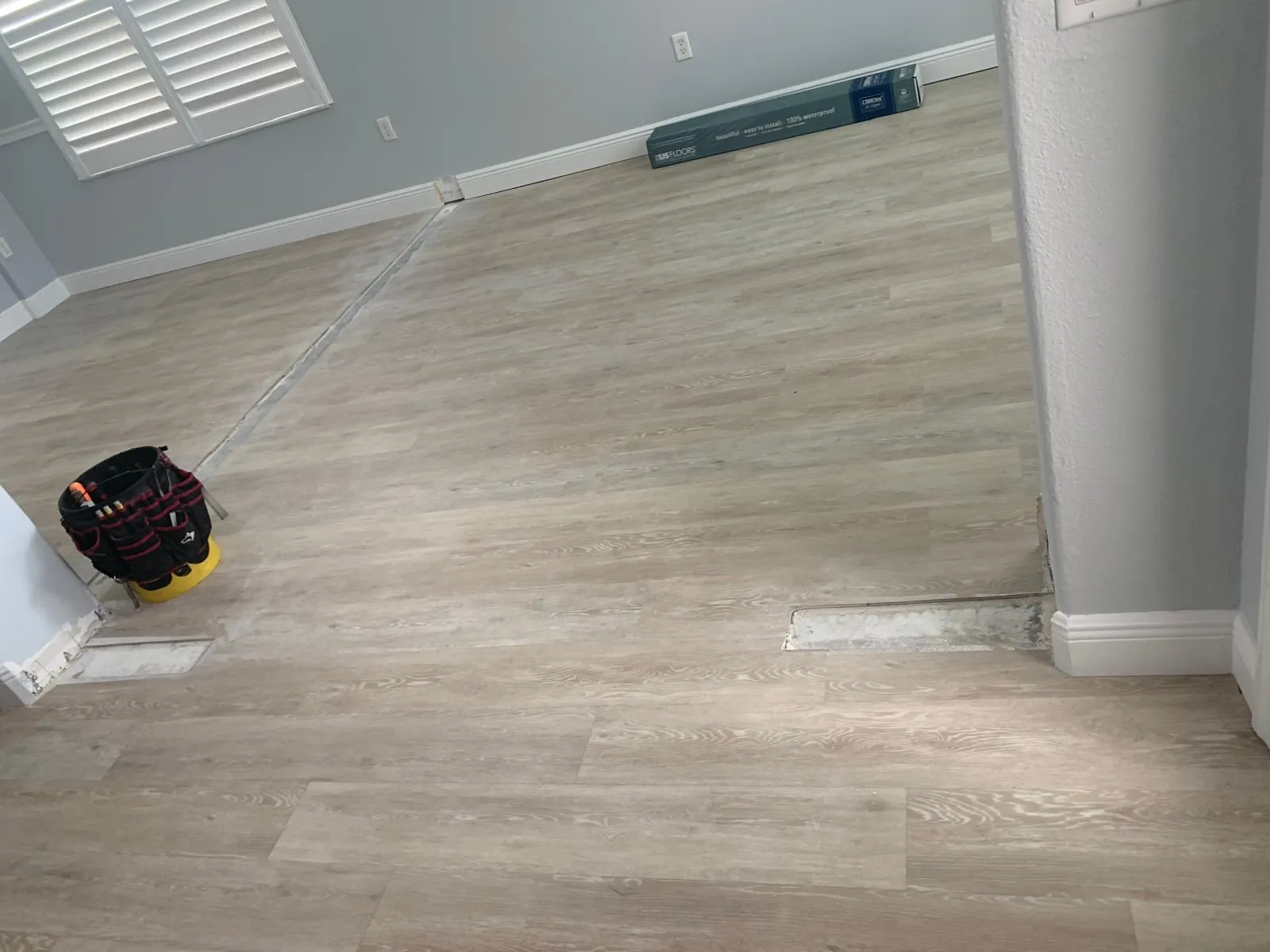 Waterproof plank flooring being installed board by board in a Sarasota home