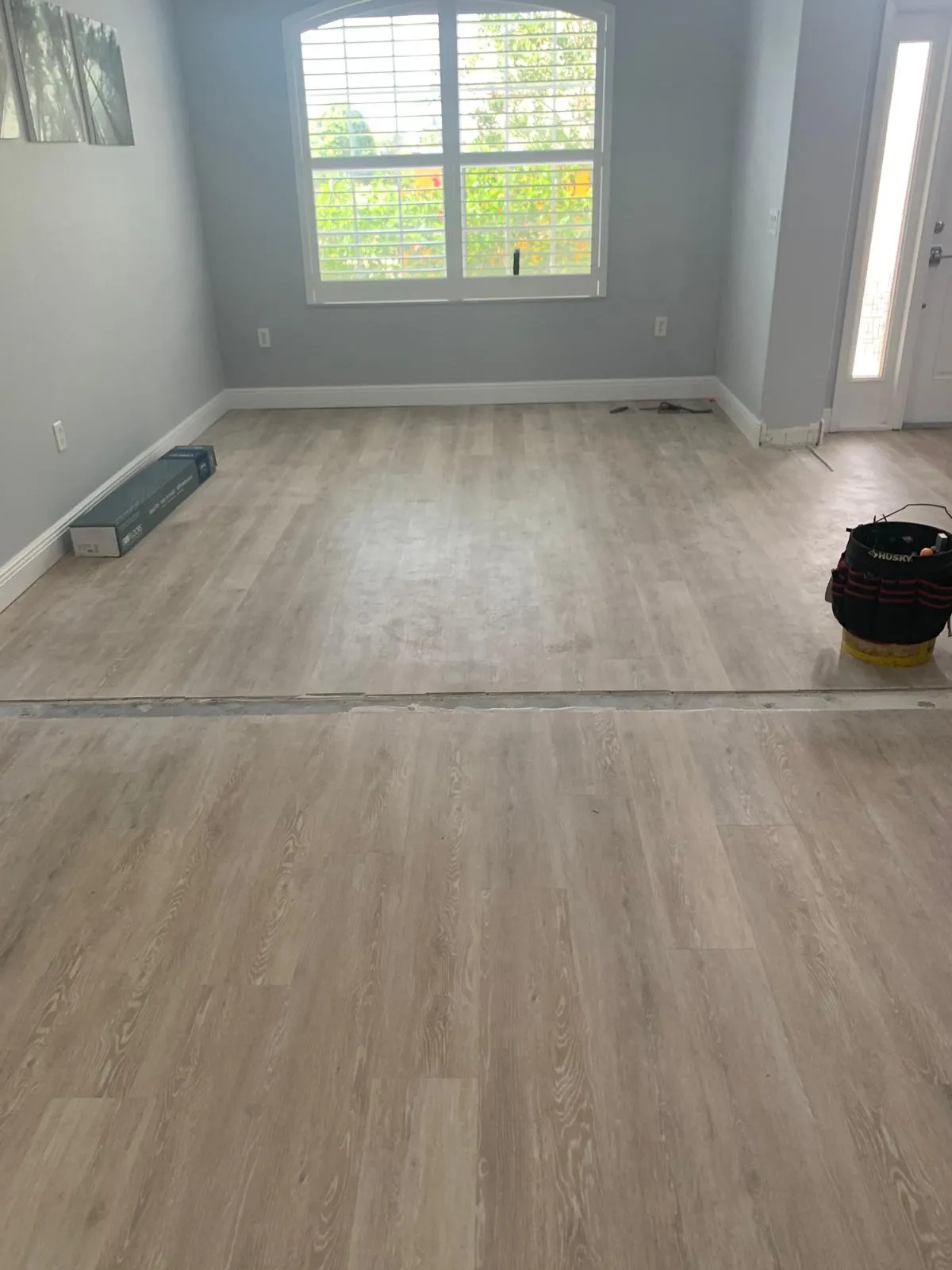 Flooring installation progressing room by room with materials staged along the wall