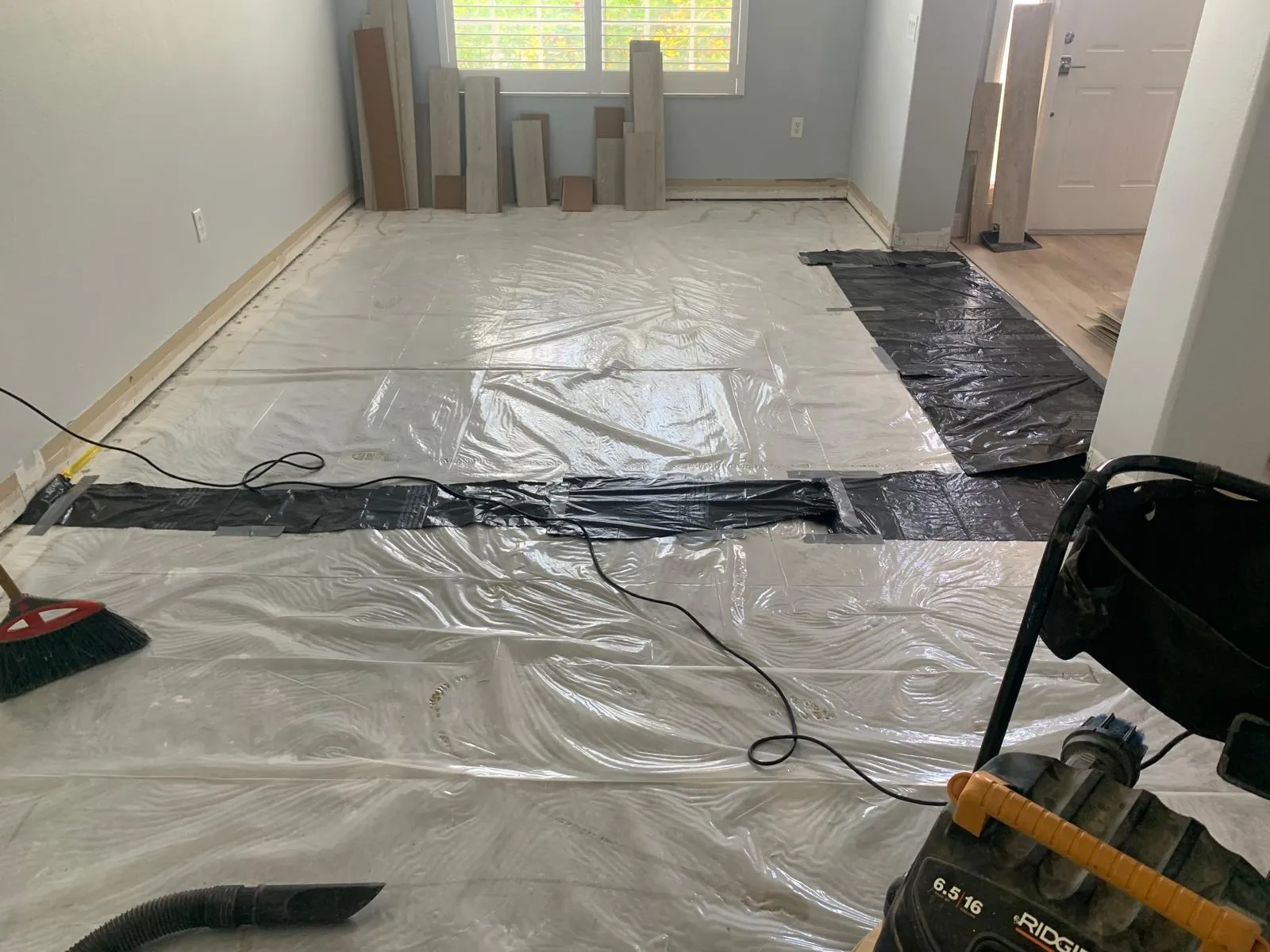 Plastic sheeting and a shop vacuum containing dust during a flooring job in Sarasota