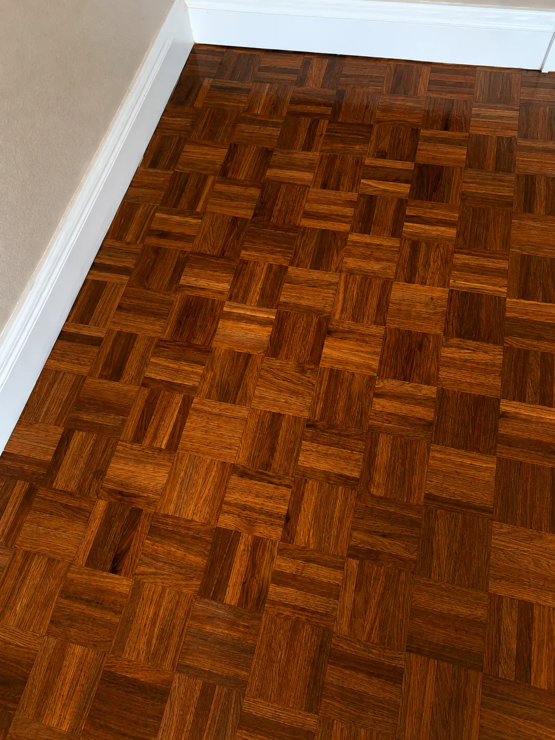 The same parquet floor refinished with a rich dark stain and glossy finish