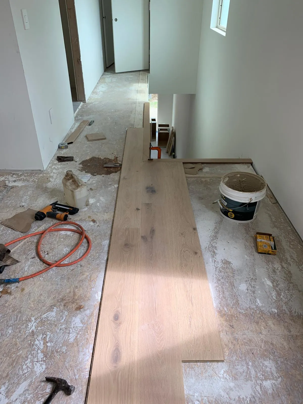 Wide-plank white oak boards being laid over the prepared subfloor